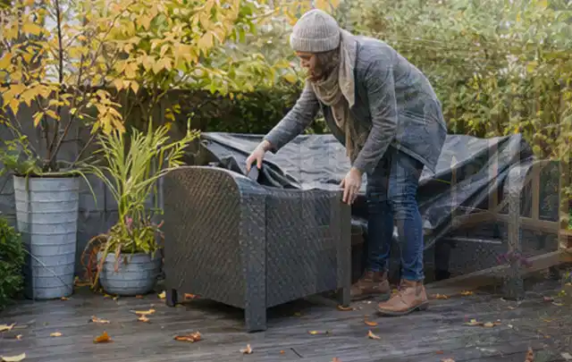 Person deckt Gartenmöbel vor der kalten Jahreszeit sorgfältig ab; Thema Aufstellpools, Schwerpunkt Checkliste; Umsetzung.