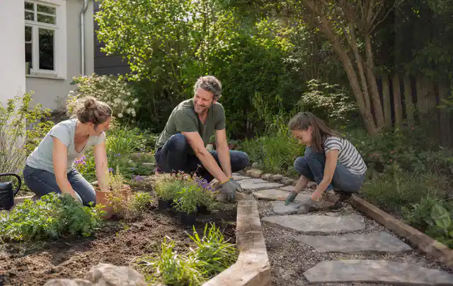 Familie geht auf einem Weg durch einen abwechslungsreich gestalteten Garten; Thema Balkon, Schwerpunkt Naturgarten; Ausgangslage.