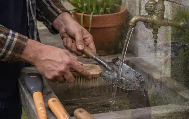 Hände reinigen gebrauchte Gartengeräte mit Bürste und Wasser am Außenbecken; Thema Bosch Indego, Schwerpunkt Leistung; Umsetzung.