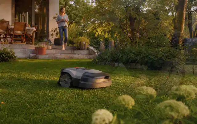 Mähroboter fährt am Abend über einen Rasen im Familiengarten; Thema Bosch Indego, Schwerpunkt Reparatur; Umsetzung.