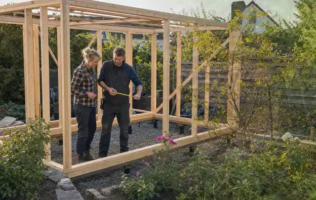 Person plant den Bau eines Gartenhauses auf einer vorbereiteten Fläche; Thema Carports, Schwerpunkt Baurecht; Ergebnis.