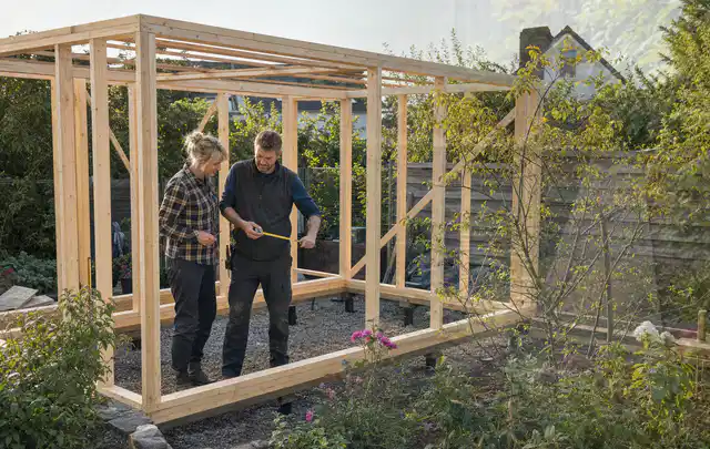 Person plant den Bau eines Gartenhauses auf einer vorbereiteten Fläche; Thema Carports, Schwerpunkt Checkliste; Praxisalltag.