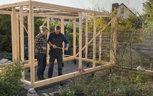 Person plant den Bau eines Gartenhauses auf einer vorbereiteten Fläche; Thema Carports, Schwerpunkt DIY; Praxisalltag.
