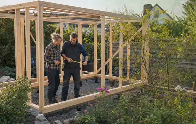 Person plant den Bau eines Gartenhauses auf einer vorbereiteten Fläche; Thema Carports, Schwerpunkt Fehlerhilfe; Ausgangslage.