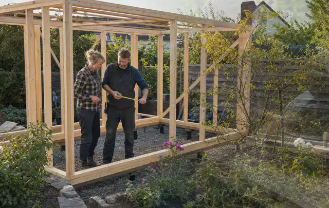 Person plant den Bau eines Gartenhauses auf einer vorbereiteten Fläche; Thema Carports, Schwerpunkt Kosten; Ergebnis.
