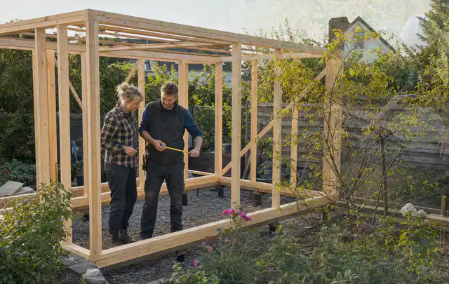 Person plant den Bau eines Gartenhauses auf einer vorbereiteten Fläche; Thema Carports, Schwerpunkt Standort; Praxisalltag.