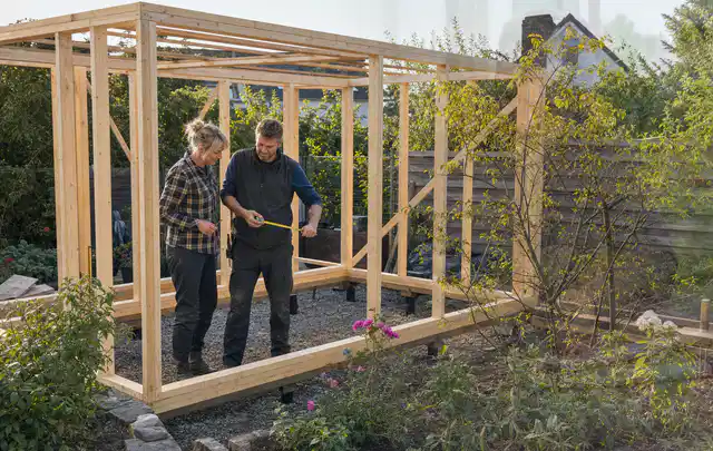 Person plant den Bau eines Gartenhauses auf einer vorbereiteten Fläche; Thema Carports, Schwerpunkt Winterschutz; Umsetzung.