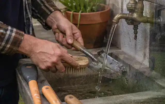Hände reinigen gebrauchte Gartengeräte mit Bürste und Wasser am Außenbecken; Thema Dreame A1, Schwerpunkt Dimensionierung; Ausgangslage.