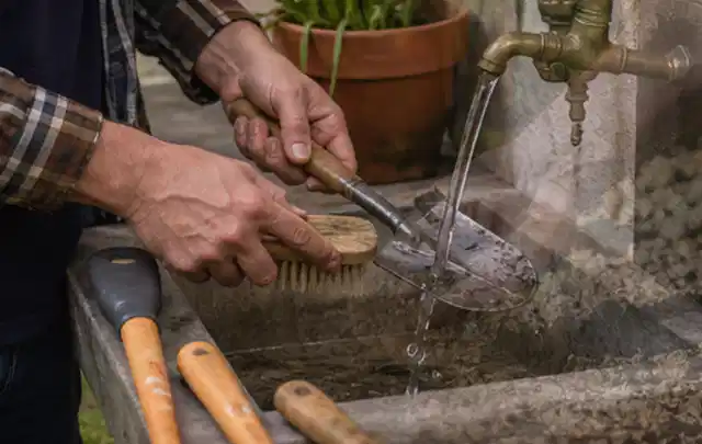 Hände reinigen gebrauchte Gartengeräte mit Bürste und Wasser am Außenbecken; Thema Dreame A1, Schwerpunkt Ersatzteile; Ausgangslage.