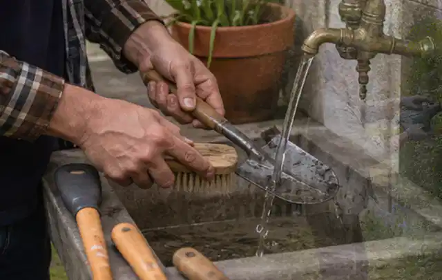 Hände reinigen gebrauchte Gartengeräte mit Bürste und Wasser am Außenbecken; Thema Dreame A1, Schwerpunkt Gärten mit kleiner Fläche; Ausgangslage.