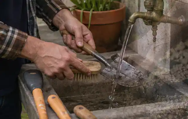 Hände reinigen gebrauchte Gartengeräte mit Bürste und Wasser am Außenbecken; Thema Dreame A1, Schwerpunkt Reinigung; Ergebnis.