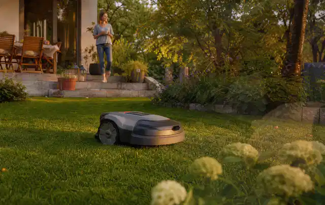 Mähroboter fährt am Abend über einen Rasen im Familiengarten; Thema Dreame A1, Schwerpunkt Sicherheit; Praxisalltag.