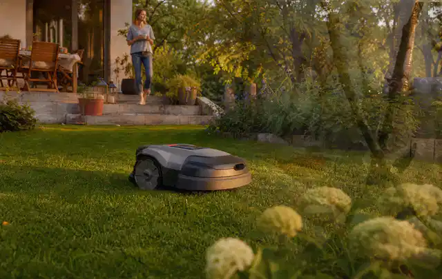 Mähroboter fährt am Abend über einen Rasen im Familiengarten; Thema Ecovacs Goat, Schwerpunkt Dimensionierung; Praxisalltag.