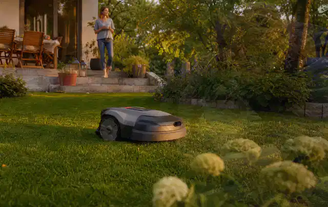 Mähroboter fährt am Abend über einen Rasen im Familiengarten; Thema Ecovacs Goat, Schwerpunkt Nachhaltigkeit; Ausgangslage.