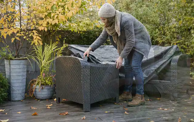 Person deckt Gartenmöbel vor der kalten Jahreszeit sorgfältig ab; Thema Einbaupools, Schwerpunkt Kosten; Umsetzung.