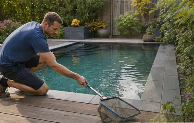Person entfernt Blätter mit einem Kescher aus einem kleinen Gartenpool; Thema Einbaupools, Schwerpunkt Reinigung; Praxisalltag.