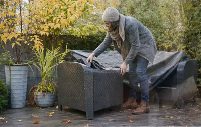 Person deckt Gartenmöbel vor der kalten Jahreszeit sorgfältig ab; Thema Einbaupools, Schwerpunkt Winterlager; Ergebnis.