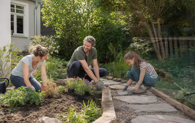 Familie geht auf einem Weg durch einen abwechslungsreich gestalteten Garten; Thema Familiengarten, Schwerpunkt Checkliste; Praxisalltag.