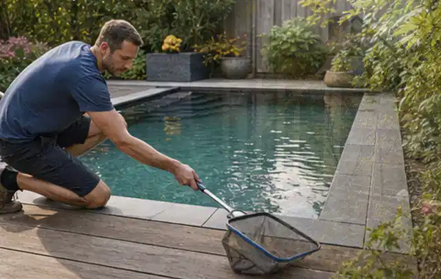 Person entfernt Blätter mit einem Kescher aus einem kleinen Gartenpool; Thema Feuerschalen, Schwerpunkt Checkliste; Ergebnis.