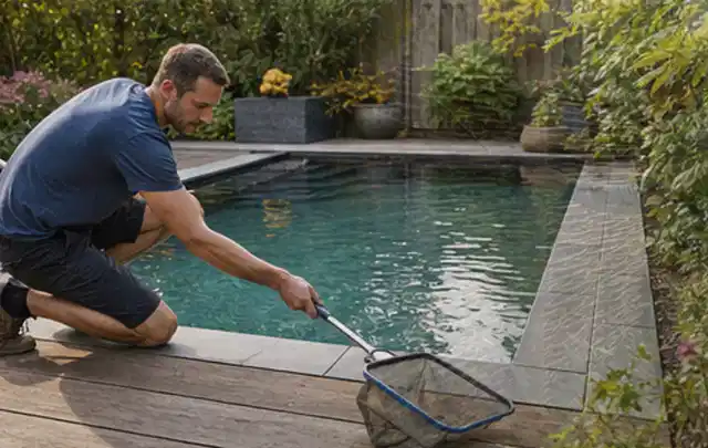 Person entfernt Blätter mit einem Kescher aus einem kleinen Gartenpool; Thema Feuerschalen, Schwerpunkt Systemvergleich; Praxisalltag.