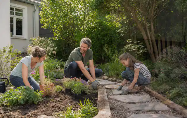 Familie geht auf einem Weg durch einen abwechslungsreich gestalteten Garten; Thema Gabionen, Schwerpunkt Standort; Praxisalltag.