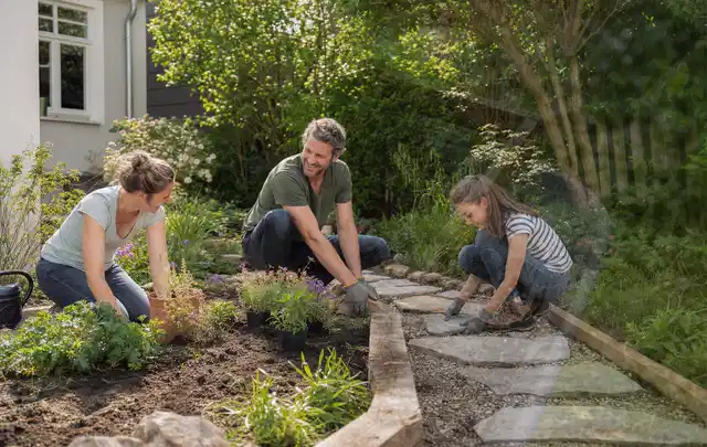 Familie geht auf einem Weg durch einen abwechslungsreich gestalteten Garten; Thema Gabionen, Schwerpunkt Winterschutz; Praxisalltag.