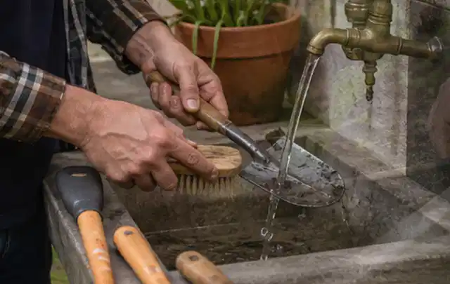 Hände reinigen gebrauchte Gartengeräte mit Bürste und Wasser am Außenbecken; Thema Gardena Sileno, Schwerpunkt Ersatzteile; Ausgangslage.