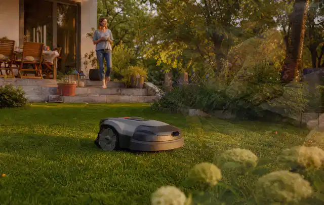 Mähroboter fährt am Abend über einen Rasen im Familiengarten; Thema Gardena Sileno, Schwerpunkt Ersatzteile; Kontrolle.