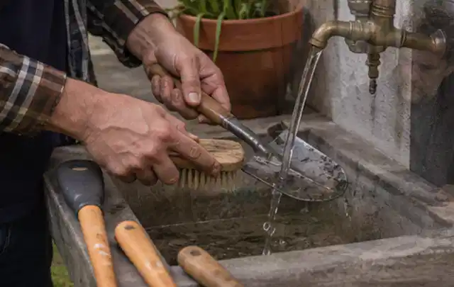 Hände reinigen gebrauchte Gartengeräte mit Bürste und Wasser am Außenbecken; Thema Gardena Sileno, Schwerpunkt Gärten mit kleiner Fläche; Umsetzung.