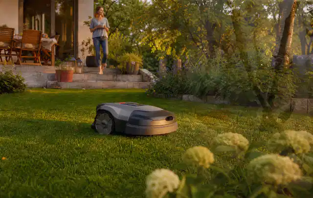 Mähroboter fährt am Abend über einen Rasen im Familiengarten; Thema Gardena Sileno, Schwerpunkt Gärten mit kleiner Fläche; Ergebnis.