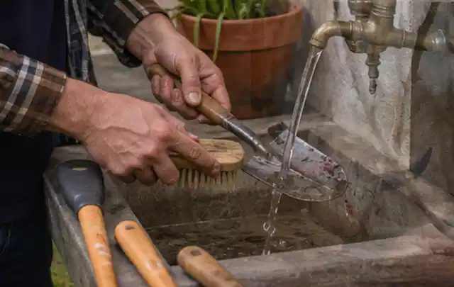 Hände reinigen gebrauchte Gartengeräte mit Bürste und Wasser am Außenbecken; Thema Gardena Sileno, Schwerpunkt Reinigung; Ausgangslage.