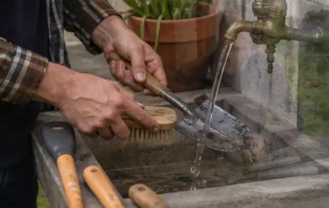 Hände reinigen gebrauchte Gartengeräte mit Bürste und Wasser am Außenbecken; Thema Gardena Sileno, Schwerpunkt Vergleich; Ergebnis.