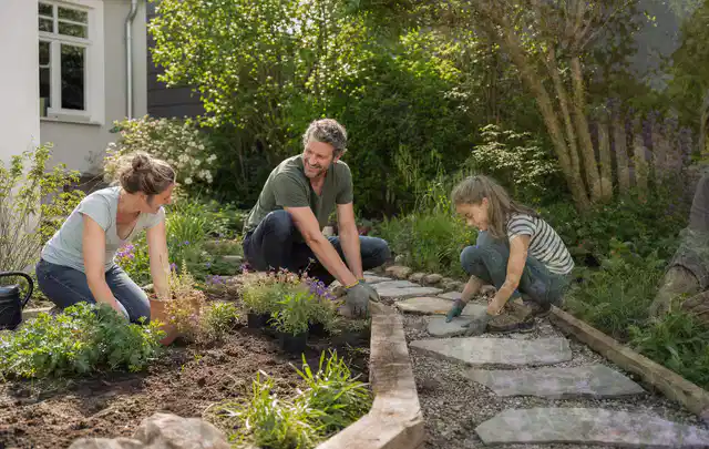 Familie geht auf einem Weg durch einen abwechslungsreich gestalteten Garten; Thema Garten am Neubau, Schwerpunkt Fehlerhilfe; Umsetzung.