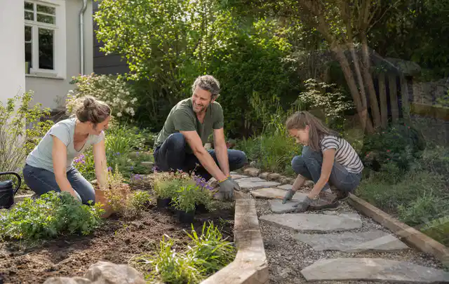 Familie geht auf einem Weg durch einen abwechslungsreich gestalteten Garten; Thema Garten am Neubau, Schwerpunkt Pflegeleichtigkeit; Ergebnis.