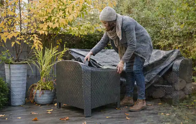 Person deckt Gartenmöbel vor der kalten Jahreszeit sorgfältig ab; Thema Gartenbeleuchtung, Schwerpunkt Checkliste; Ergebnis.