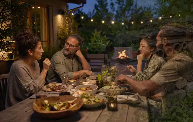 Menschen verbringen einen ruhigen Abend an einem Sitzplatz im Garten; Thema Gartenbeleuchtung, Schwerpunkt Outdoor Freizeit; Umsetzung.