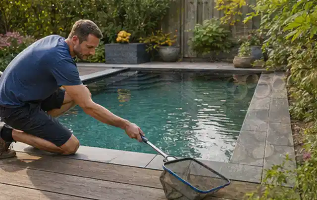 Person entfernt Blätter mit einem Kescher aus einem kleinen Gartenpool; Thema Gartenbeleuchtung, Schwerpunkt Reinigung; Ausgangslage.