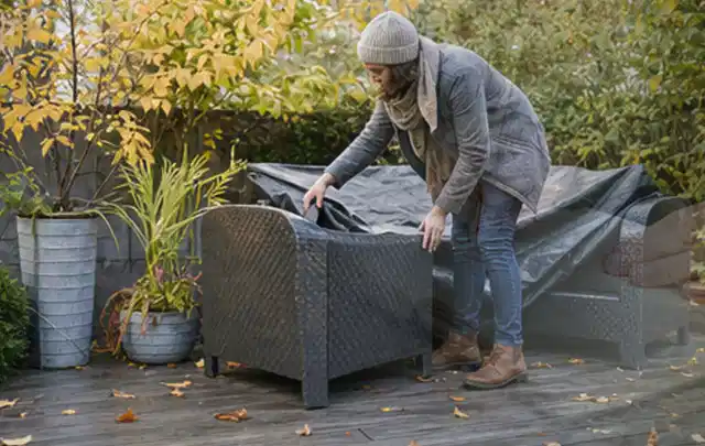 Person deckt Gartenmöbel vor der kalten Jahreszeit sorgfältig ab; Thema Gartenbeleuchtung, Schwerpunkt Vergleich; Ergebnis.