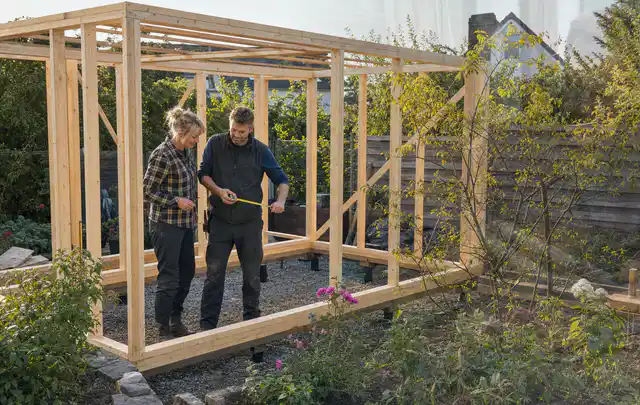 Person plant den Bau eines Gartenhauses auf einer vorbereiteten Fläche; Thema Gartenhaus Aufbau, Schwerpunkt Checkliste; Kontrolle.
