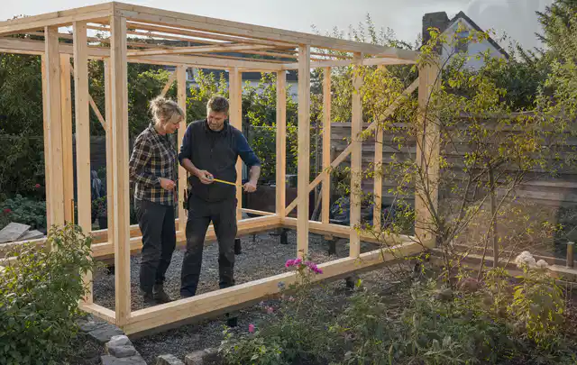 Person plant den Bau eines Gartenhauses auf einer vorbereiteten Fläche; Thema Gartenhaus Aufbau, Schwerpunkt Kosten; Umsetzung.