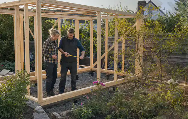 Person plant den Bau eines Gartenhauses auf einer vorbereiteten Fläche; Thema Gartenhaus Aufbau, Schwerpunkt Nachhaltigkeit; Kontrolle.