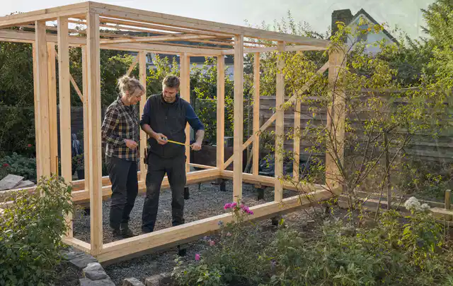 Person plant den Bau eines Gartenhauses auf einer vorbereiteten Fläche; Thema Gartenhaus aus Holz, Schwerpunkt Baurecht; Praxisalltag.