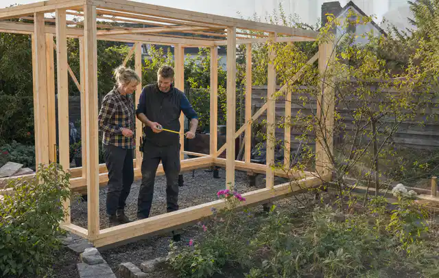 Person plant den Bau eines Gartenhauses auf einer vorbereiteten Fläche; Thema Gartenhaus aus Holz, Schwerpunkt DIY; Praxisalltag.