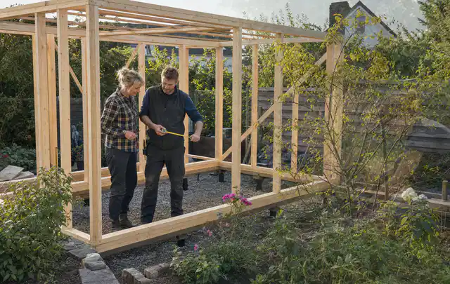 Person plant den Bau eines Gartenhauses auf einer vorbereiteten Fläche; Thema Gartenhaus aus Holz, Schwerpunkt Fundament; Praxisalltag.