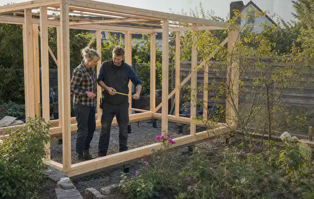 Person plant den Bau eines Gartenhauses auf einer vorbereiteten Fläche; Thema Gartenhaus aus Holz, Schwerpunkt Kosten; Ausgangslage.