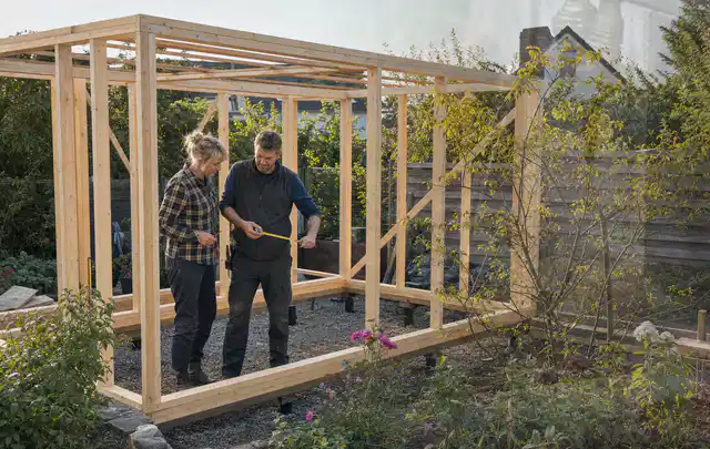 Person plant den Bau eines Gartenhauses auf einer vorbereiteten Fläche; Thema Gartenhaus aus Holz, Schwerpunkt Materialwahl; Kontrolle.