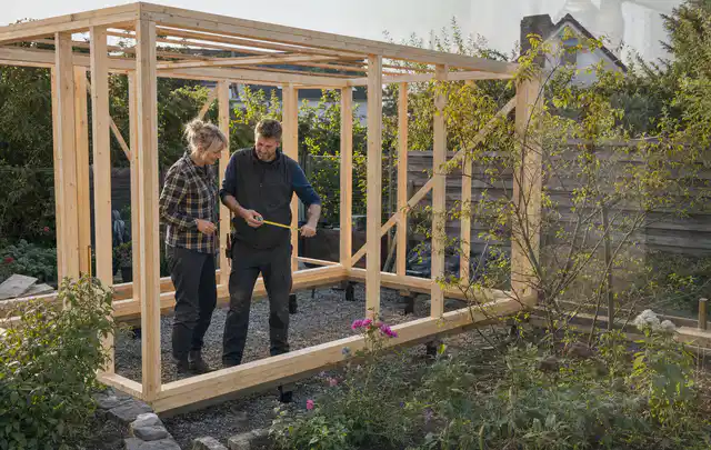 Person plant den Bau eines Gartenhauses auf einer vorbereiteten Fläche; Thema Gartenhaus aus Holz, Schwerpunkt Nachhaltigkeit; Praxisalltag.