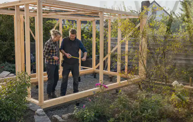 Person plant den Bau eines Gartenhauses auf einer vorbereiteten Fläche; Thema Gartenhaus aus Holz, Schwerpunkt Winterschutz; Kontrolle.