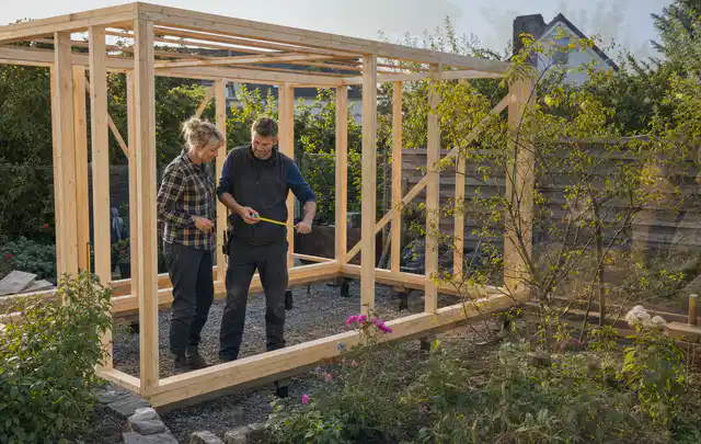 Person plant den Bau eines Gartenhauses auf einer vorbereiteten Fläche; Thema Gartenhaus aus Kunststoff, Schwerpunkt Winterschutz; Ausgangslage.