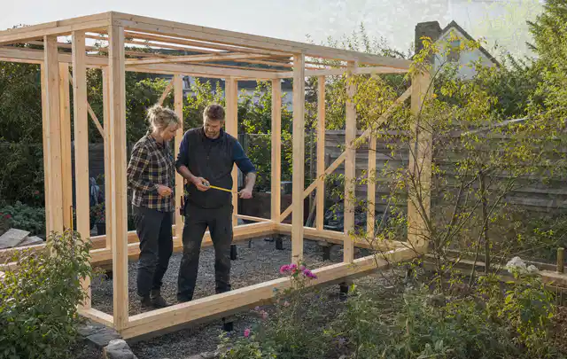 Person plant den Bau eines Gartenhauses auf einer vorbereiteten Fläche; Thema Gartenhaus aus Metall, Schwerpunkt Checkliste; Kontrolle.